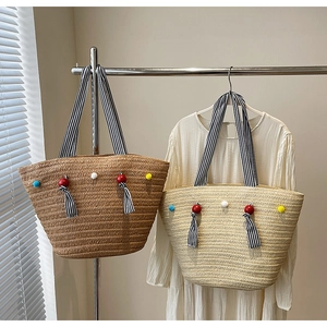 Détail du sac cabas en paille tissée avec perles colorées et pompon pour les vacances