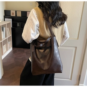 Vue détaillée d'un grand sac cabas vintage marron porté par un mannequin dans une pièce