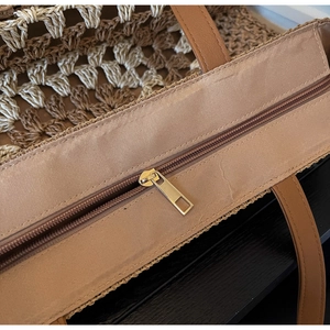 Detailed close-up of handmade straw tote bag weave with secure zipper and leather handle