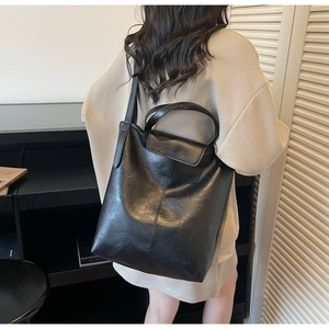 Détail d'un sac cabas en cuir noir avec rabat magnétique et logo de mode embossé