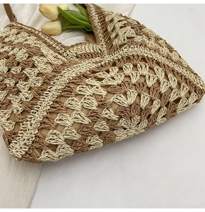 Détail du sac cabas en paille bicolore montrant le crochet en losange et les anses en cuir