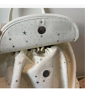 Detailed macro view of white canvas backpack with silver star pattern and magnetic metal buckle