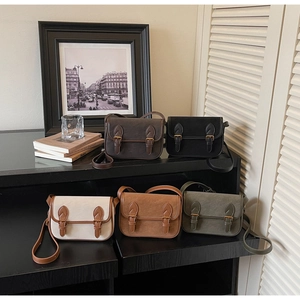 Détail de sacs bandoulière rétro en cinq couleurs sur un meuble minimaliste noir