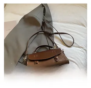 Detail of vintage brown leather handbag featuring dual decorative buckles and a top handle