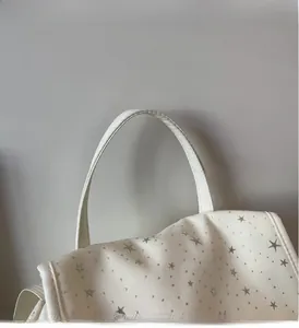 Close-up of a reinforced white canvas handle with silver stars on a mini backpack