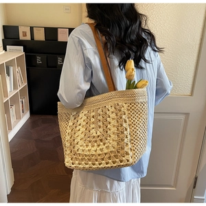 Detail of handwoven straw tote bag with 3D floral pattern and brown leather straps