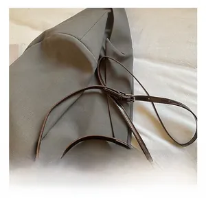 Close-up of adjustable slim shoulder strap with metal buckle on brown baguette bag