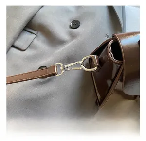 Close-up of polished silver metal hook and strap connector on a dark brown bag