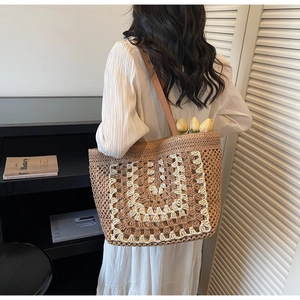 Detailed view of bohemian woven straw tote bag with brown straps and U-shaped pattern