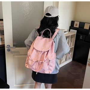 Detailed back view of pink backpack with silver star patterns and drawstring design