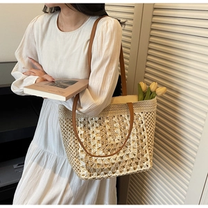 Detail of hand-woven straw tote with hollow pattern and brown leather straps