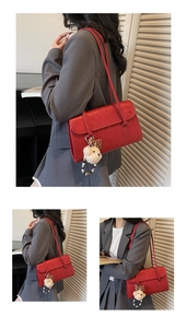 Detail view of red leather shoulder bag with polka dot bow plush bear charm