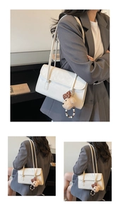 Detail of minimalist cream faux leather shoulder bag featuring a cute plush bear charm