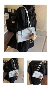 Detail of light blue shoulder bag with a cute brown polka dot bear charm accessory