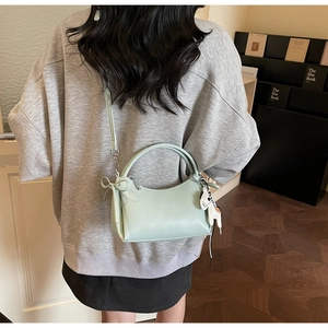 Detail der minzgrünen Baguette-Tasche mit Lederschleife und Zebra-Anhänger am Model