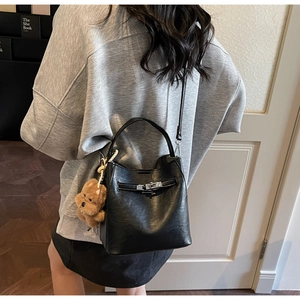 Détail du sac seau vintage en cuir ciré noir avec breloque ours et bandoulière
