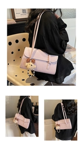 Detail of pink PU leather underarm bag with a cute bear charm pendant on the side