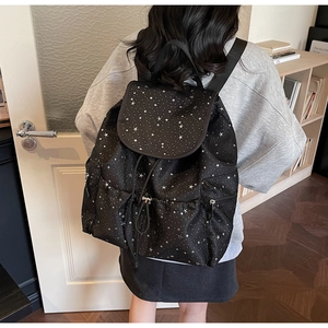 Close-up of black backpack with star sequin pattern worn in a casual indoor setting