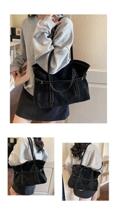 Macro shot showing white contrast stitching and adjustable buckle on black leather tote bag
