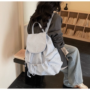 Detail view of the light blue backpack featuring silver star prints and side zipper pockets