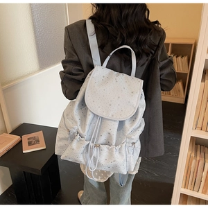 Detail of light blue backpack with silver star pattern shown in a library setting