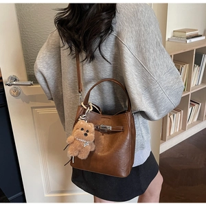 Sac seau vintage en cuir ciré marron avec fermoir argenté et pendentif ours sur modèle