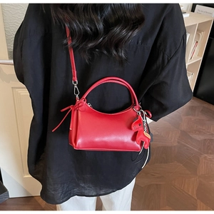 Détail du sac à bandoulière en cuir rouge avec breloque cheval sur modèle en chemise