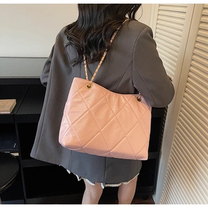 Sac cabas en cuir matelassé rose avec bandoulière chaîne dorée porté par un mannequin