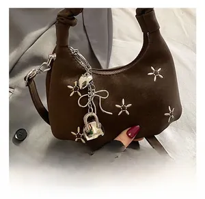 Detail of coffee brown cloud bag featuring white flower embroidery and metal pendants