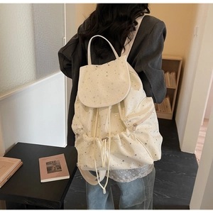 Detailed back view of a beige canvas backpack with star prints and drawstring closure