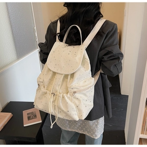 Ivory backpack with silver star patterns shown on model in a real-life daily usage scene