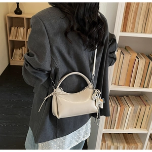 Detail of beige soft leather crescent bag with horse pendant and slender shoulder strap