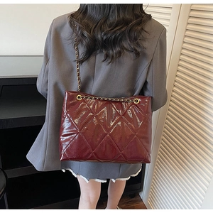Détail du sac cabas en cuir matelassé bordeaux avec chaîne dorée élégante