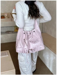 Detail view of pink biker-style tote bag with zippers and rivets worn by a model