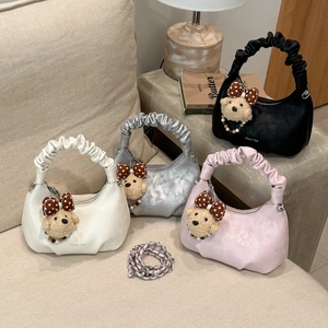 Détails de quatre sacs nuage plissés colorés avec breloques d'ours sur un canapé