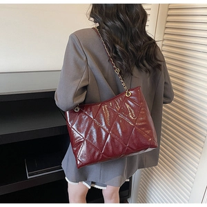 Vue détaillée d'un sac cabas bordeaux matelassé avec finition brillante et chaîne dorée