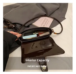 Vue intérieure du sac bandoulière en cuir verni marron montrant sa grande capacité