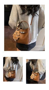 Detail of a brown leather bucket bag with metal lock and cute teddy bear pendant charm