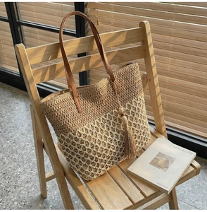 Detail of hollow-out woven tote bag with fringe wood bead tassel on a wooden chair