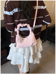 Pink quilted shoulder bag with ruffle handle and bow charm worn with casual outfit