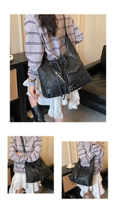 Detail view of large black retro tote bag with punk rivets, metal zippers and multi-pockets