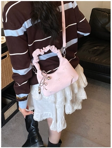 Pink pleated dumpling bag with star embroidery and metallic heart charms in use