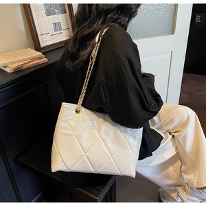 Détail d'un sac cabas blanc matelassé avec bandoulière chaîne dorée sur un mannequin