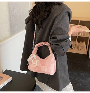 Detailed shot of pink pleated handbag with pearl lace bow and metal chain strap