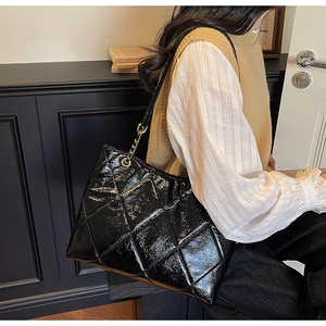 Détail du grand sac cabas matelassé en cuir verni noir avec bandoulière en chaîne dorée