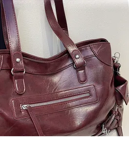 Close-up of deep wine red textured leather tote with silver rivets and zippers