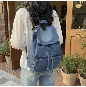 Photo de sac à dos en jean avec fermeture à rabat, cordon de serrage et poche zippée inférieure
