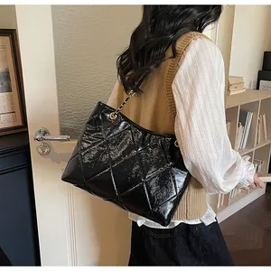 Sac fourre-tout noir matelassé avec chaînes dorées porté par un mannequin en salle