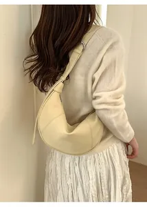 Detail view of cream-white crescent shoulder bag with adjustable side buckle and strap