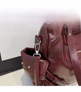 Detail of burgundy textured leather tote with silver rivets and polished metallic hardware